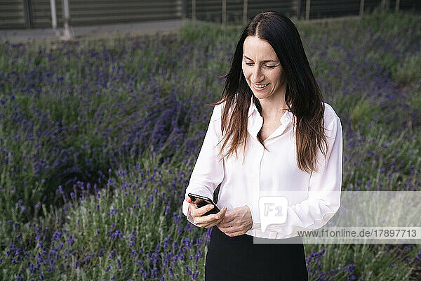 Happy mature woman using mobile phone in park