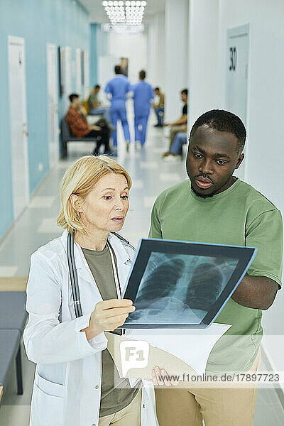 Patient discussing over X-ray image with doctor in hospital corridor