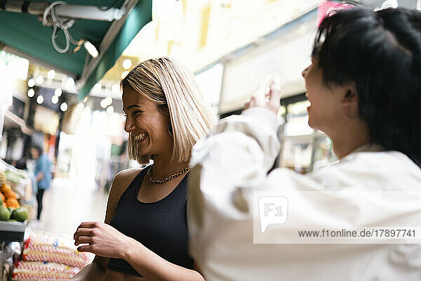 Happy young woman shopping with friend at concession stand