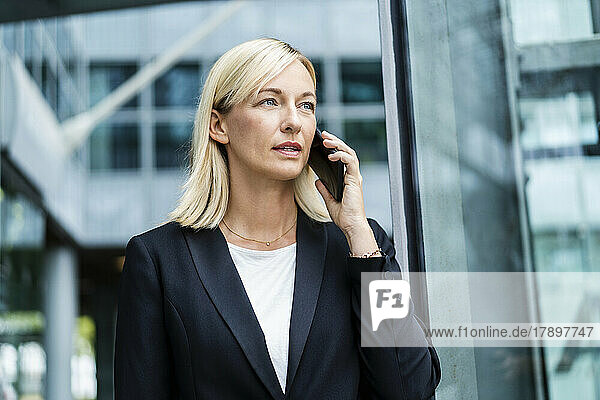 Businesswoman talking on phone standing in front of building