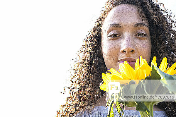 Schöne Frau mit Sommersprossen  die Sonnenblume hält