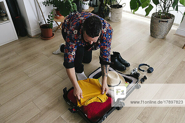 Man packing clothes in suitcase at home