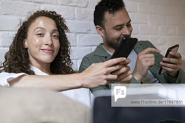 Smiling businesswoman with colleague using smart phone in office