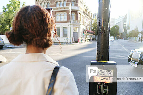 Frau wartet am Fußgängerüberweg-Knopf