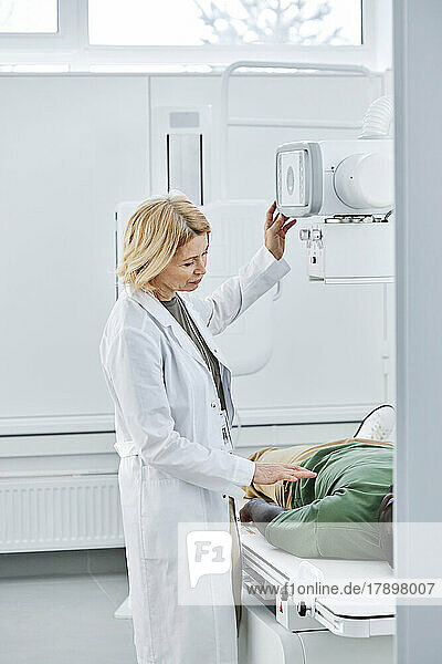 Arzt spricht mit Patient  der in der Klinik auf einem Röntgengerät liegt