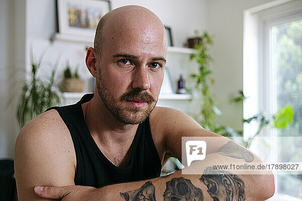 Man with mustache and tattoo at home