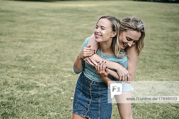 Happy blond woman hugging friend in park