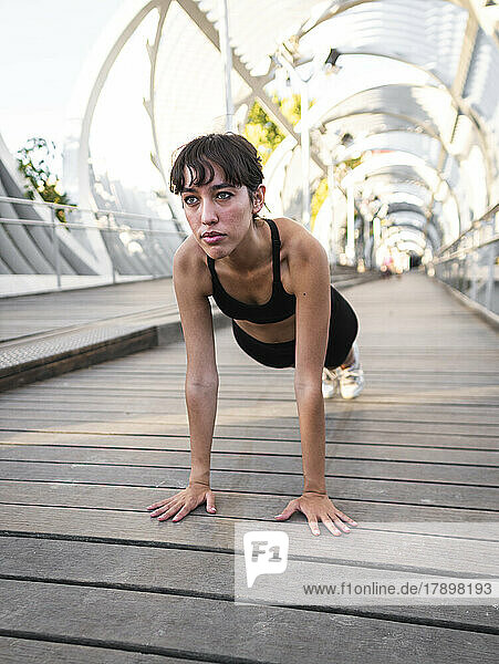 Young sportswoman practicing push-ups on footpath