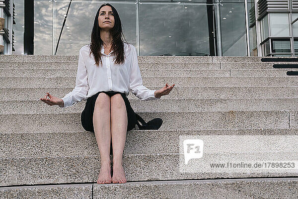 Thoughtful businesswoman doing meditation sitting on steps