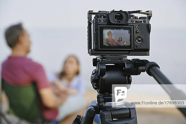 Camera recording video of father and daughter at beach