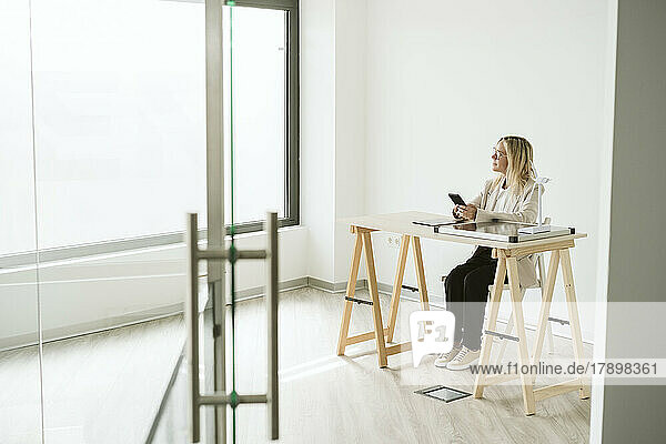 Woman sitting at desk in office with mobile phone and solar panel