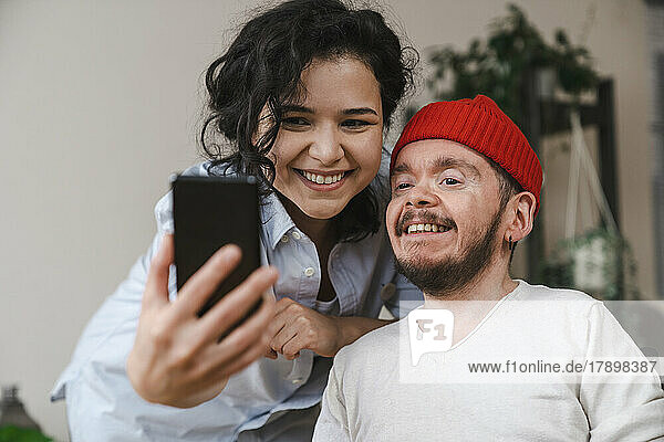 Happy girlfriend and boyfriend taking selfie through smart phone at home