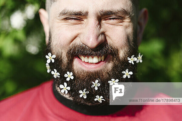 Glücklicher Mann mit kleinen weißen Blumen am Bart