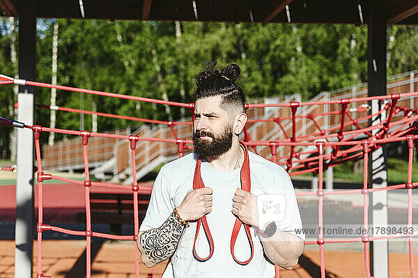 Bearded man with resistance band in park on sunny day