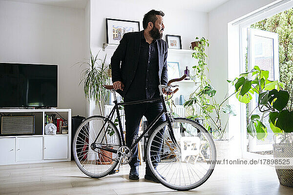 Businessman standing with bicycle in living room at home