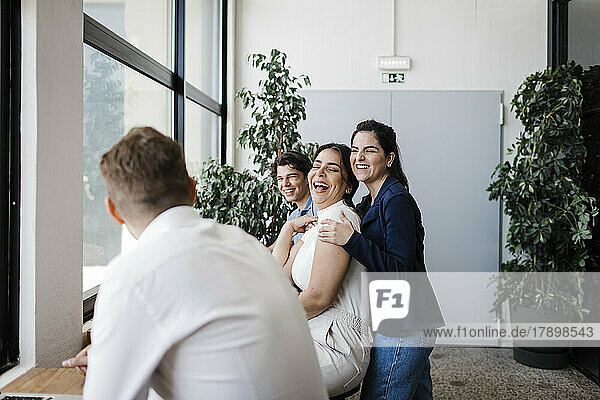 Businesswoman laughing with colleagues in modern office