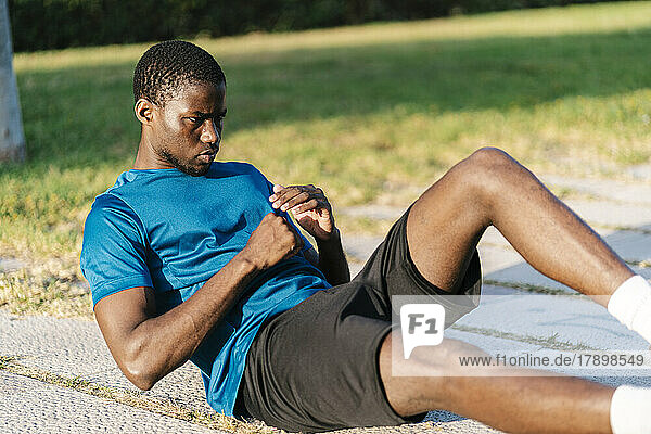 Young man exercising at park on sunny day