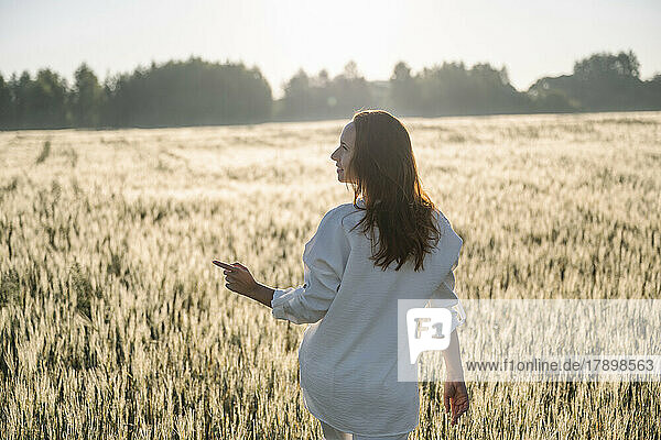 Woman pointing walking in cornfield on sunny day