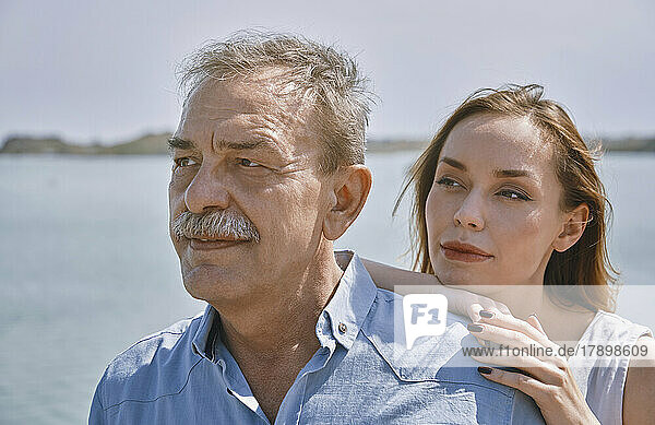Thoughtful young woman standing with father next to sea