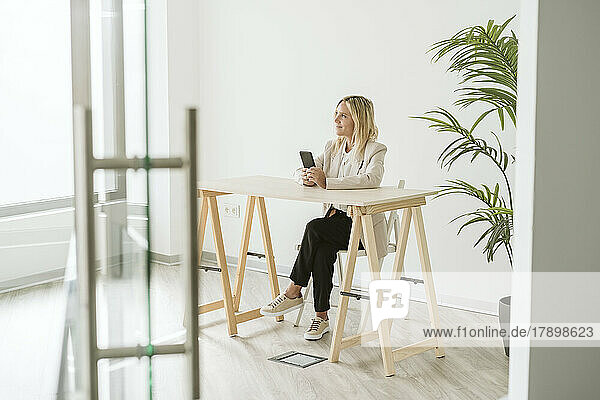 Businesswoman using mobile phone at desk in modern office