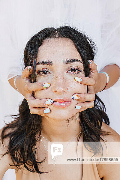 Hands massaging face of young woman