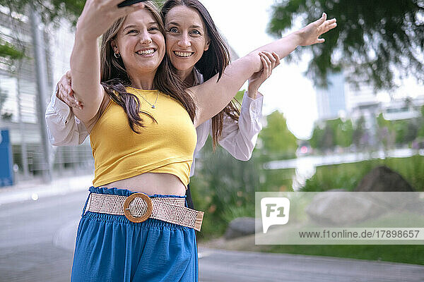 Cheerful women taking selfie through smart phone in park