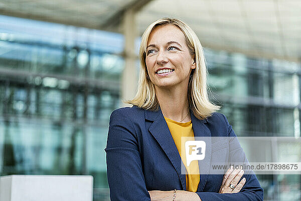 Businesswoman with arms crossed standing in front of building