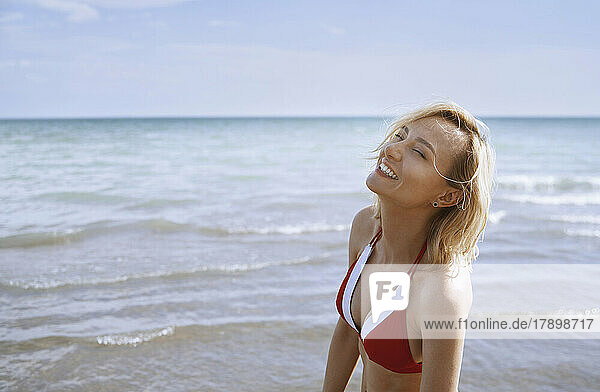 Smiling woman enjoying sunlight at beach