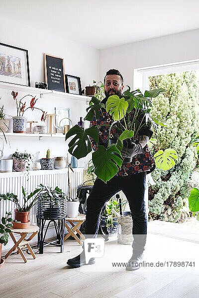 Man standing with potted plant at home