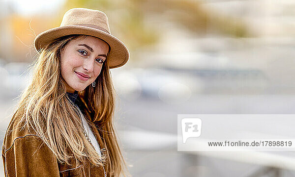 Smiling young woman with long blond hair wearing hat