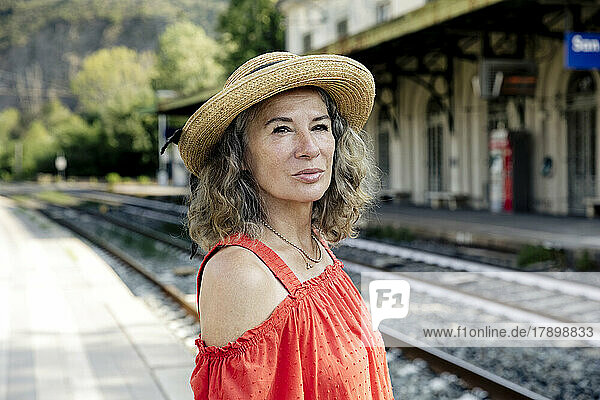 Woman wearing hat waiting for train at railroad station