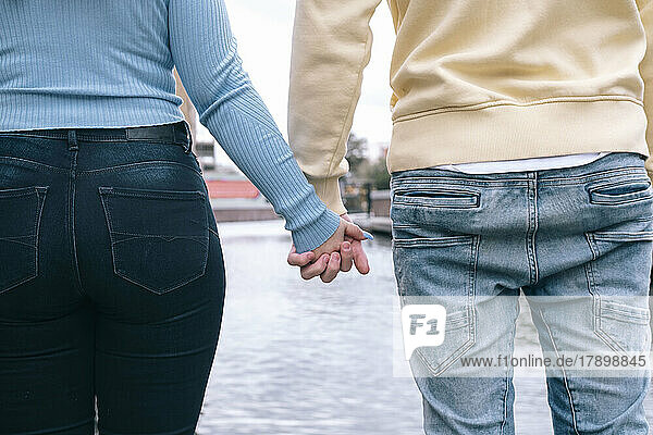 Young couple holding hands together in front of river