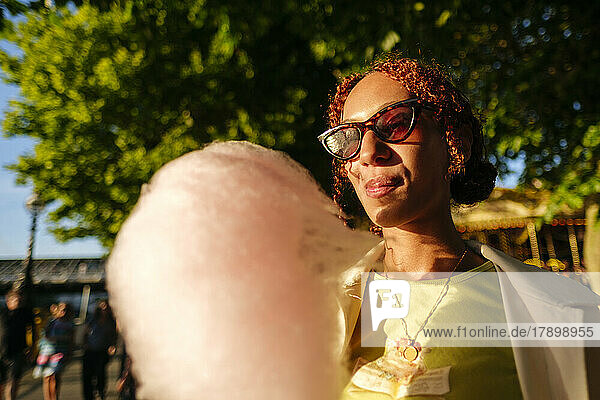 Young woman wearing sunglasses enjoying cotton candy