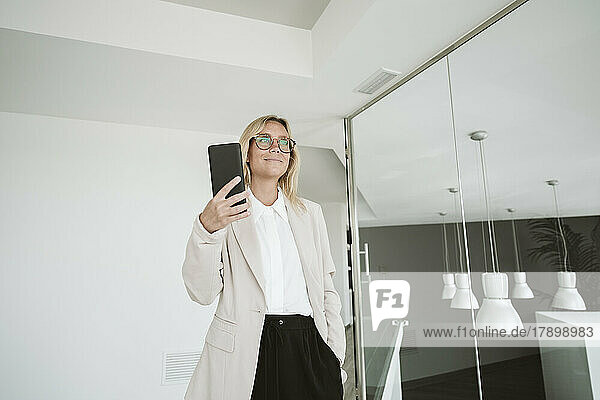 Businesswoman in modern office holding mobile phone