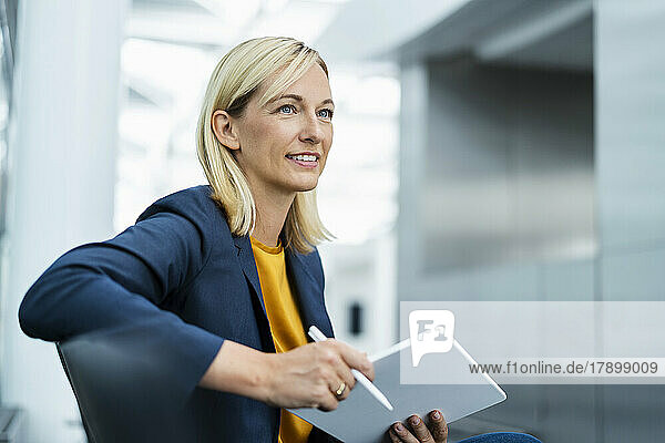 Smiling businesswoman sitting with tablet PC