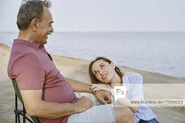 Father talking with daughter sitting at beach