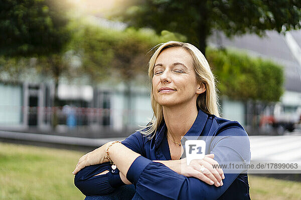 Businesswoman with eyes closed sitting at park