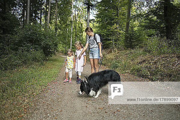 Woman with daughters and pet dog on footpath in forest