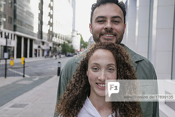 Smiling woman with curly hair standing in front of friend