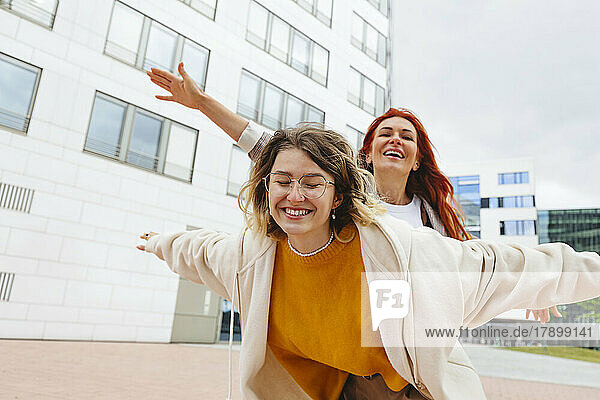 Happy mother and daughter with arms outstretched at Hafencity