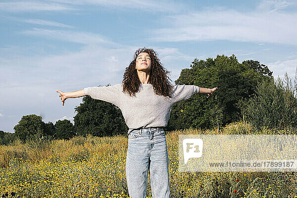 Carefree woman with arms outstretched standing in field