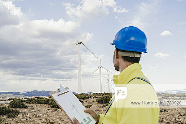 Ingenieur mit Dokument zur Betrachtung von Windkraftanlagen im Windpark