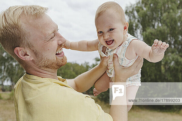 Cheerful baby girl having fun with father in park