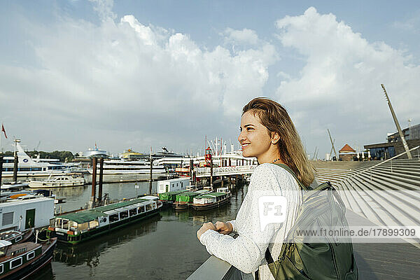 Glückliche Frau steht am Geländer und blickt auf den Hamburger Hafen