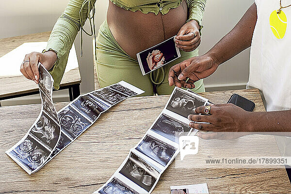 Schwangere Frau arrangiert Ultraschallfoto des Babys mit Mann zu Hause