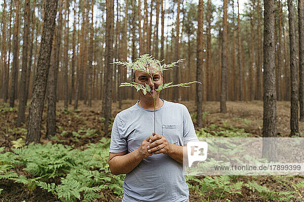 Mature man holding plant in front of his face