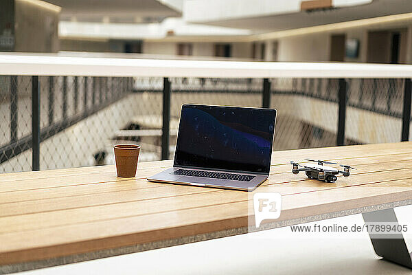 Laptop and drone with coffee cup on table at office