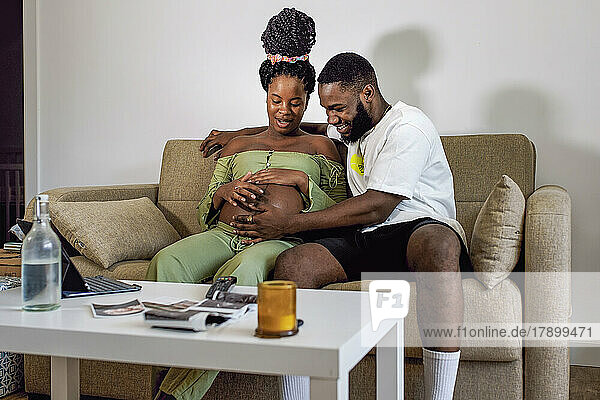 Pregnant woman sitting on sofa with boyfriend at home