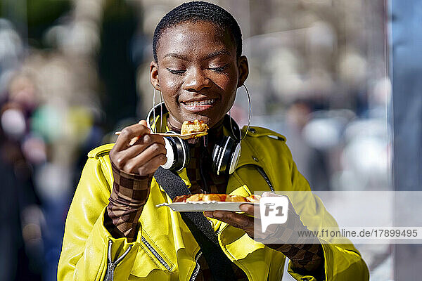 Woman holding plate eating food from spoon