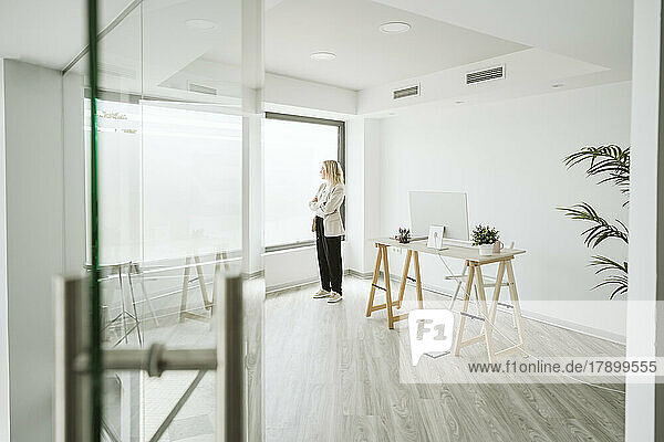 Businesswoman in modern office looking out of window